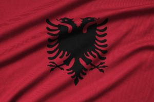Albania flag is depicted on a sports cloth fabric with many folds. Sport team waving banner